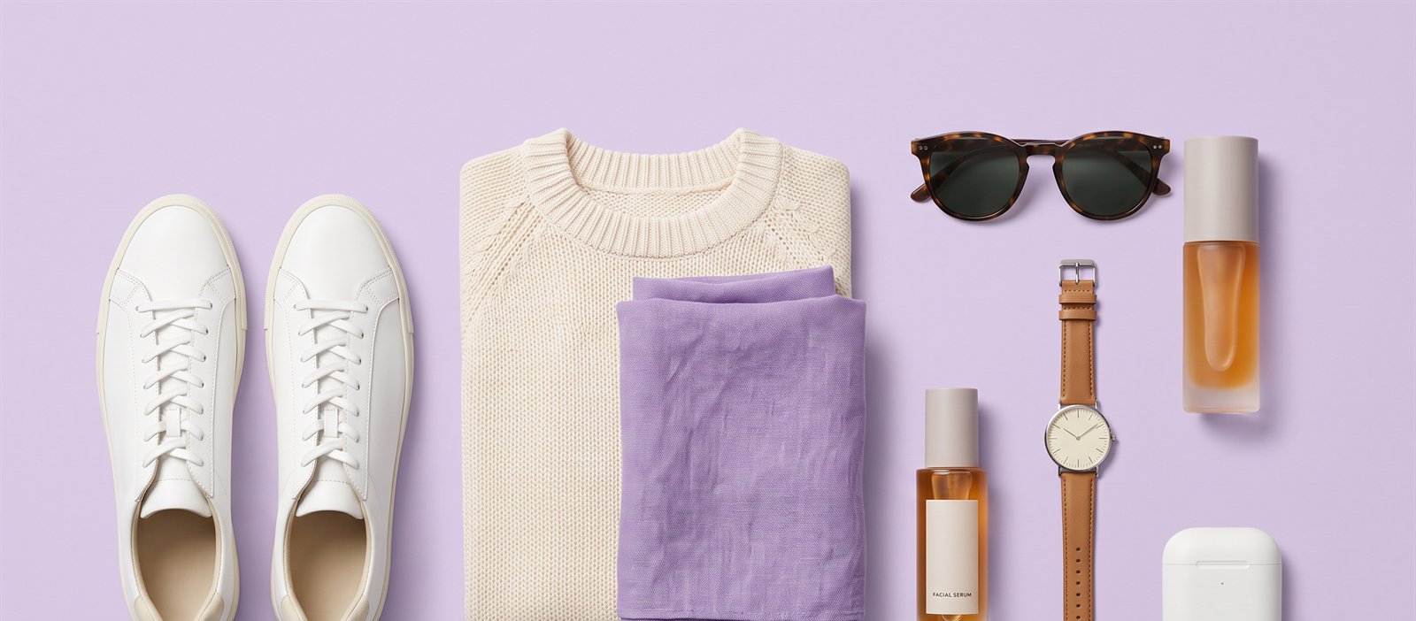 Flat lay of sneakers, knitwear, sunglasses, a watch and cosmetics
